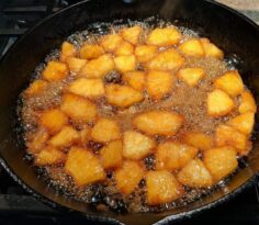 pineapples cooking in brown sugar in cast iron skillet