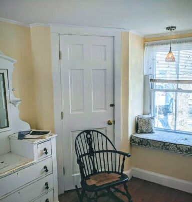 yellow room with white dresser, chair and window seat